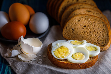 still life with an eggs, rye bread and sandwich. Low key photography, rustic style