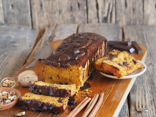 Place for text. Holiday homemade chocolate pumpkin long rectangular cupcake, glazed with chocolate, ready to eat on a kitchen board.