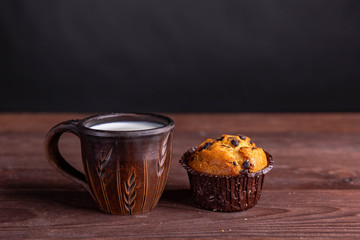 clay mug with milk and muffin on a wooden table