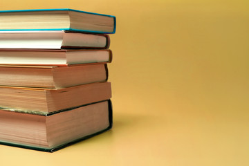 Books stacked on a yellow background with copy space.