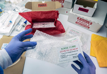 Nurse unpacking box with Covid-19 PCR kit in hospital warehouse, conceptual image