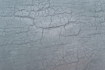 Texture of cracked gray paint on an old weathered wall. Dirty peeling paint on an outdoor surface. Grunge background