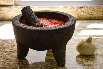 Spicy red sauce made with tomato in a Traditional Mexican molcajete at kitchen