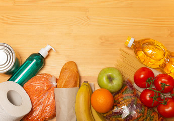 Food delivery service. Buy products online during quarantine. Healthy food and antiseptic on wooden background. Sunflower oil, tomatos, pasta, bread, lentils, caned food, toilet paper, sanitizer.