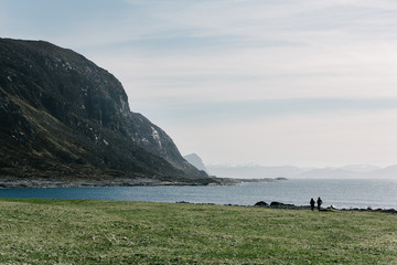 Fototapeta na wymiar Idyllic scenery: silhouets of two people walking by the shore of Godøy island, Norway.