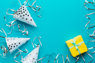 Blue caps, silver serpentine and yellow gift on a blue paper background. Holiday background. Copy space