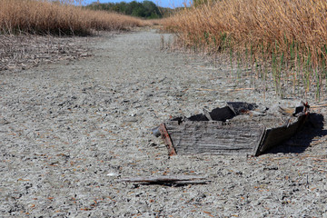 old sunken boat appears in a river bed that has dried up due to drought