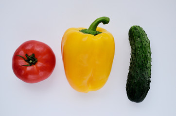 red tomato yellow pepper green cucumber over the top on a white background