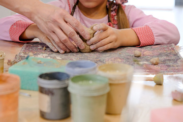 A child molds a product from clay in a modeling lesson.