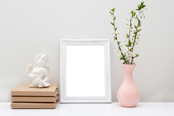 Empty white frame mock up with pink vase and books on the table. Wooden frame mockup for your text.