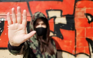 Coronavirus and air pollution concept. The girl wears a protective mask to protect against coronavirus and shows a stop hand gesture to stop the outbreak of the corona virus. © Yevhen Roshchyn