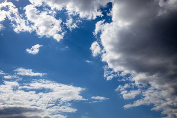 Fototapeta na wymiar blue sky on a sunny warm day with white and gray clouds