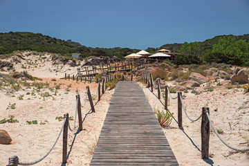 A walkway leads to the sunny beaches, and to the clear and transparent waters of the island of Maddalena in Sardinia, Italy.