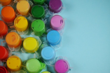 multicolored paint in jars on a blue background with copy space