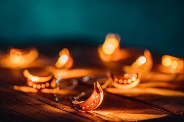 Ramadan Moon with Colorful Light Glowing at Night and Glittering with Bokeh Lights on Ground. Festive Greeting Card, Muslim Holy Month Ramadan Kareem. Blue Dark background. Ramadan Crescent / New Moon