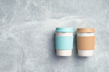 Reusable bamboo coffee cups on stone background. Eco-friendly take away coffee mugs. Zero waste, sustainable lifestyle concept. Flat lay, top view