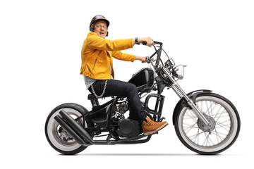 Obraz na płótnie Canvas Mature biker in a yellow leather jacket riding a chopper motorbike