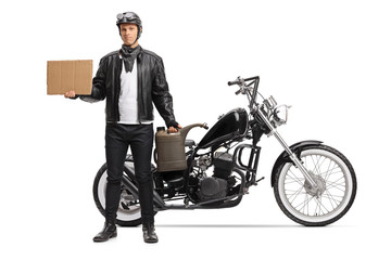 Young biker holding a gas container and a blank cardboard sign and standing next to a chopper