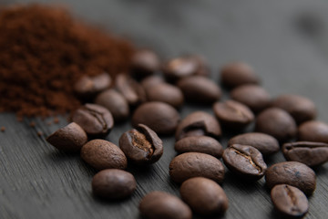 Detalle de granos de café y café molido, sobre base de madera obscura