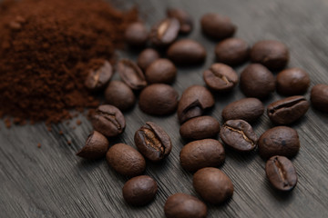 Detalle de granos de café y café molido, sobre base de madera obscura