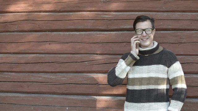 Happy young man with eyeglasses talking on the phone in autumn