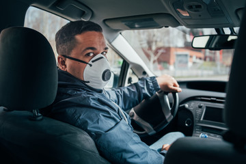 young hispanic taxi driver wearing a protective mask and talks to a client.