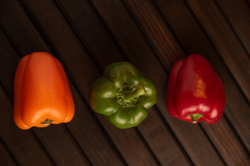 Pimiento ,morrón en tres colores, sobre base de madera obscura