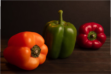 Pimiento ,morrón en tres colores, sobre base de madera obscura