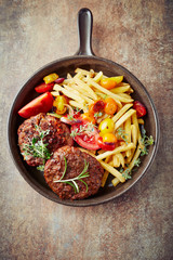 Fried hamburger steaks with tomatoes and french fries. Rustic background. Top view.	