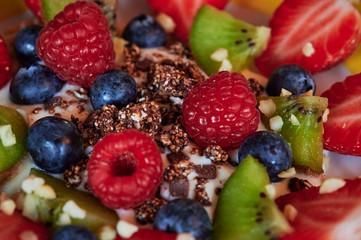 Macro shot of a bowl with various fruits and yogurt as a healthy and vegan snack.