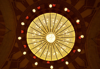 A beautiful massive intricate chandelier hanging in the middle of the dome of Al Fateh Grand Mosque . Al Fateh mosque is one of the largest mosque in the world