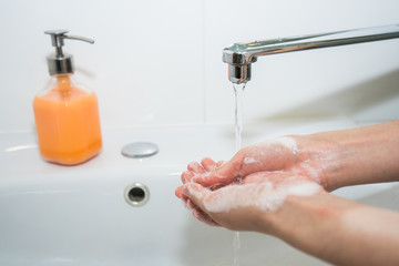 Hand washing with soap. Girl washes her hands with antibacterial soap for the prevention of coronavirus covid-19 2019-ncov and flu. Sink, faucet, hands and soap. Minimalist bathroom