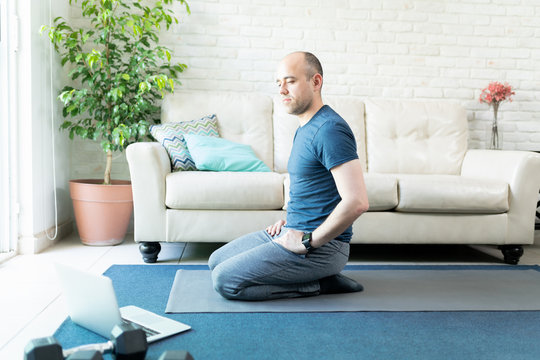 Man Doing Yoga From A Laptop Computer At Home