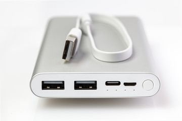 Fototapeta premium An additional stand-alone power bank for charging mobile devices. External battery isolated on a white background. White charger for smartphone with power supply. Shallow depth of field (DOF).