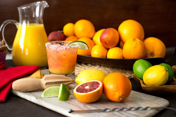 A mixed tequila drink sits on a cutting board after being made with freshly squeezed fruits.