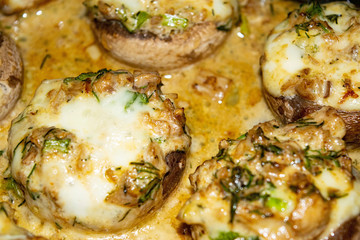 Mushrooms baked in the oven with cheese, green onions and dill. Close up.