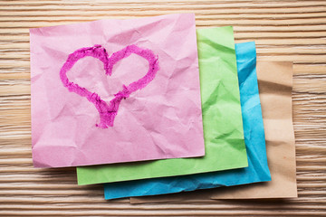 Heart is drawn on multi colored crumpled sticky notes