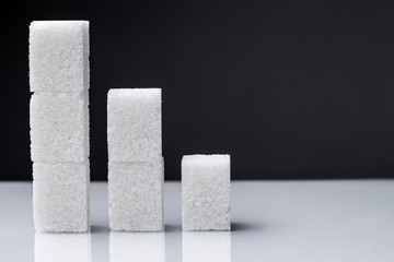 The downward chart is made up of sugar cubes. Sugar reduction in consumption сoncept.
