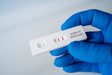 Doctor holding a Positive Result for COVID-19 with test kit for viral disease COVID-19 2019-nCoV. Lab card kit test for coronavirus SARS-CoV-2 virus. Fast test COVID-19. - obrazy, fototapety, plakaty