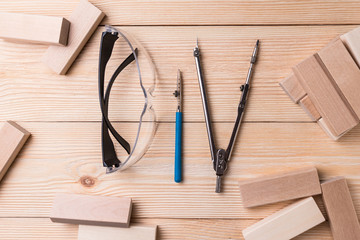 Safety glasses, drawing accessories and wooden blocks. Items on the table look like letters DIY (do it yourself).