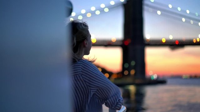 Concept of scenic cityscape and evening sightseeing on water boat, millennial carefree hipster tourist using instant camera for photographing Manhattan island during voyage trip on Hudson river
