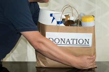 Concept of charity and helping others: a volunteer collects a donation bag of food cleaning...