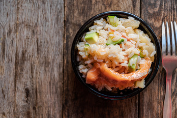 Poke salad, view from the top, in a black ceramic bowl on a wooden table.