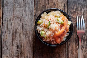 Poke salad, view from the top, in a black ceramic bowl on a wooden table.
