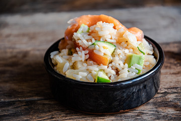 Poke salad in a black ceramic bowl on a wooden table.