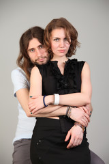 Portrait of young couple in love posing at studio dressed in classic clothes