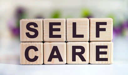 SELF CARE - text on wooden cubes on a floral background with tulip buds