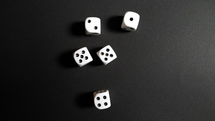 White and black dice disorganized over black background.
