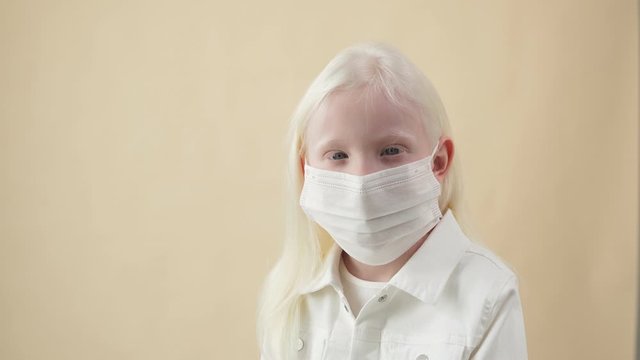 Coronavirus, covid-19 concept. Little unusual albino child in medical mask, isolated in studio background.