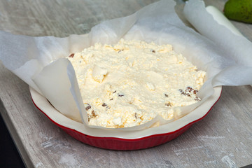 raw curd dough in a round ceramic baking dish.